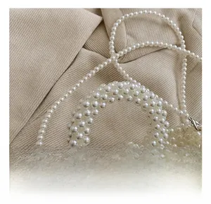 Close-up of handmade white pearl woven handbag with reinforced handle and metal clasp