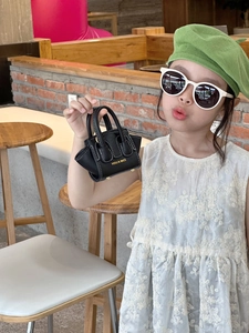 Détail d'un mini sac noir pour enfants avec coutures blanches et logo doré imprimé