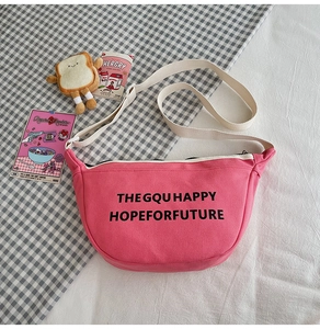 Détail du sac bandoulière en toile rose avec imprimé lettres et sangle beige réglable