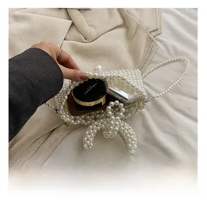 Detail showing the internal capacity of a white pearl beaded handbag with makeup items