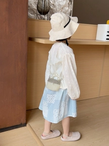 Little girl wearing a pearl crossbody bag with a lace top and plaid skirt for summer