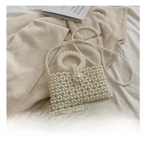 Detail of hand-woven white pearl handbag showing beaded texture and round ring handle