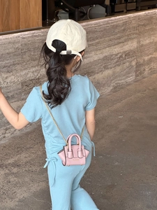 Mini sac bandoulière rose avec chaîne dorée porté par un enfant en tenue gaufrée