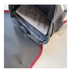Internal view of grey school backpack showing drawstring closure and spacious red-lined main compartment