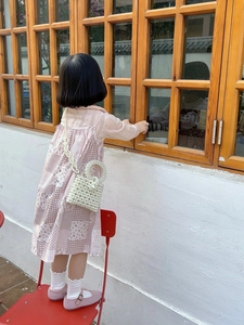Detail of a girl wearing a white pearl woven handbag with a pink floral patchwork dress