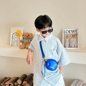 Stylish blue round crossbody bag for kids featuring white cool letter printing on front
