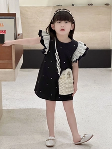 Detail of elegant girls' black dress featuring pearl accents and mini pearl crossbody bag