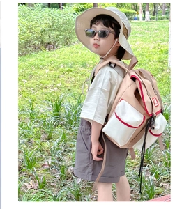 Detail of a kids outdoor backpack with color-blocking design and red piping on a boy
