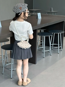 Detail of child wearing a pink shell-shaped crossbody bag with pearl mesh and strap