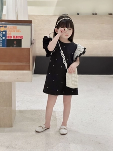 Detail of a chic girls' black polka dot summer dress with white ruffled sleeves