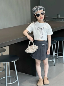 Detail shot of girls' white T-shirt with bow print and grey pleated skirt outfit