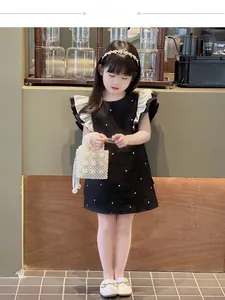 Detail of elegant black girls' dress with ruffle shoulders and pearl accents with handbag