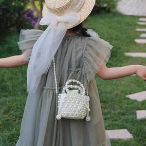 Sac à main en perles blanches pour filles avec chaîne bandoulière sur fond de jardin