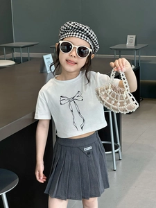 Fashionable girl's outfit featuring white bow t-shirt, pleated skirt, and pearl handbag