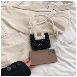Detail of handmade black woven bead bag with white pearl chain and handle