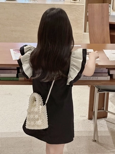 Detailed back view of a white pearl beaded mini crossbody bag for kids on a child model