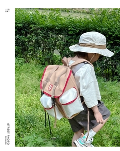 Close-up of children backpack with red trim, white pockets and outdoor scenic background