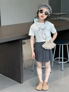 Full view of girl wearing french style pleated skirt with a pearl woven crossbody bag