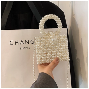 Close-up of white imitation pearl woven handbag with a round handle and beaded strap
