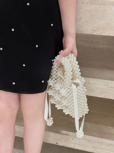 Close-up of handmade cream pearl beaded handbag with drawstring satin lining