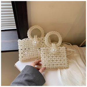 Detail of white faux pearl woven handbags with round handles and decorative large pearl clasp
