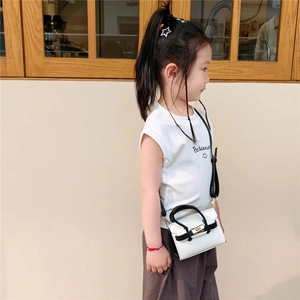 Vue latérale détaillée d'un mini sac en cuir blanc avec poignée noire sur un enfant mannequin
