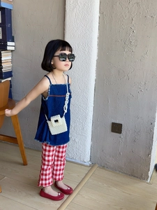 Detail showing elegant pearl beaded crossbody bag for kids with denim top and plaid pants