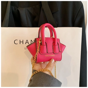 Gros plan d'un mini sac bandoulière fuchsia en cuir grainé avec chaîne dorée