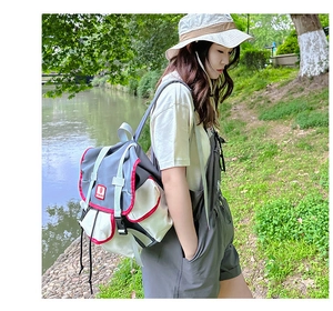 Detail of color-block grey and beige backpack with red trim and buckle on outdoor background