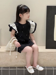 Detail of elegant black girls' dress with contrasting white ruffled sleeves and pearls