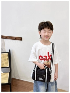 Schwarze Kinder-Umhängetasche mit gestreiften Trägern und Fashion-Logo an einem Model