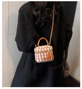Detail of checkered plaid mini bucket bag with leather handles and gold chain strap