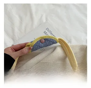 Detail of cream canvas tote bag featuring a blue plaid handle cover with pink snap button