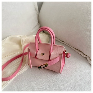 Détail du mini sac à main rose avec texture grainée et boucle en métal sur tissu blanc