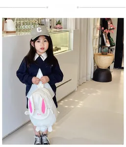 Detail of cute white rabbit backpack featuring pink long ears and plush tail on a girl
