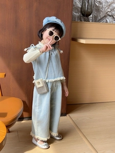 Detailed view of kids denim outfit with fringe edges and pearl strap crossbody bag