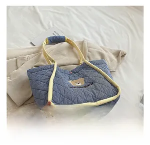 Detail of blue quilted canvas tote bag featuring cute bear embroidery and yellow handles