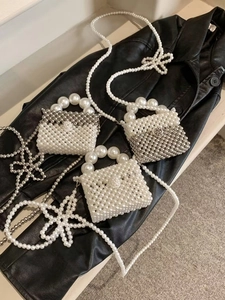 Detail of handmade woven mini pearl handbag with white beads and elegant handle