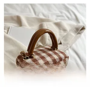 Detail show of plaid wool mini bucket bag featuring a brown leather handle and gold hardware