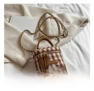 Top view of mini plaid bucket bag with gold chain strap on white fabric background