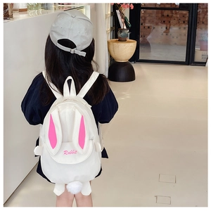 Detail view of a white rabbit backpack with pink ears and cute pom-pom tail on a child