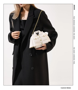 Macro detail of jacket-shaped white crossbody bag with gold buttons and chain strap