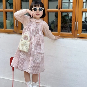 Girl in pink floral dress and knit cardigan holding a white pearl woven mini handbag