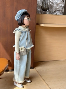 Detail of light blue girls' denim suit featuring embroidery, fringe, and a pearl chain bag