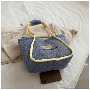 Close-up of blue quilted tote bag with cute bear embroidery and yellow rope handles