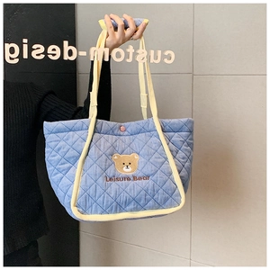 Close-up of blue quilted tote bag featuring a cute embroidered bear and Leisure Bear text