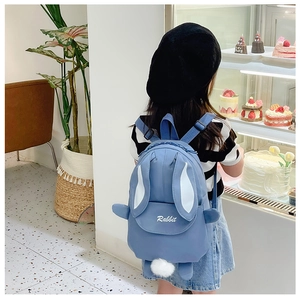 Detail of light blue rabbit backpack for girls with long ears and soft white plush pom-pom
