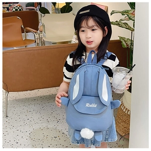 Detail of blue rabbit ears kids backpack with pom-pom tail on a little girl model