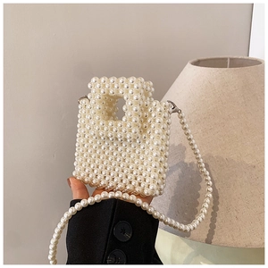 Chic cream pearl beaded mini handbag with crossbody strap shown in a minimalist setting