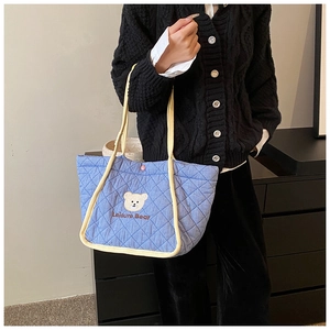 Close-up of light blue quilted tote bag with cute bear embroidery and cream trim